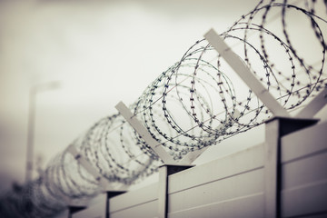 Shallow depth of field (selective focus) and filtered image with a razor wire on the outside wall...