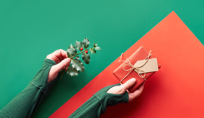 Panoramic Christmas flat lay in biscay green and red colors with Xmas decorations in triangular paper hole in a shape of Christmas tree.