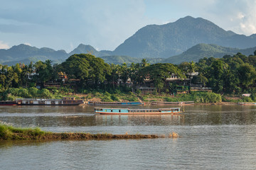 Traditional Long Boat on the Mekong River and mountains view in Luang Prabang, Laos.