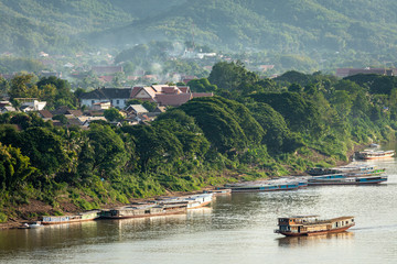 Traditional Long Boat on the Mekong River and mountains view in Luang Prabang, Laos.