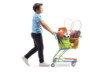 Boy walking and pushing a mini cart with sport items