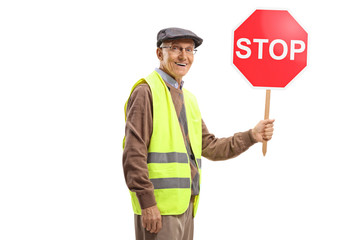 Elderly man wearing safety vest and holding a stop sign