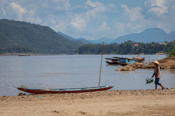 Fototapeta na wymiar Traditional Long Boat on the Mekong River and mountains view in Luang Prabang, Laos.