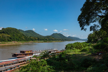 Fototapeta premium Traditional Long Boat on the Mekong River and mountains view in Luang Prabang, Laos.