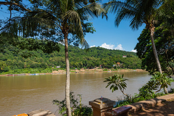 Traditional Long Boat on the Mekong River and mountains view in Luang Prabang, Laos.