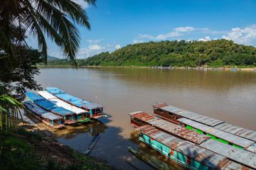 Traditional Long Boat on the Mekong River and mountains view in Luang Prabang, Laos.