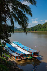 Traditional Long Boat on the Mekong River and mountains view in Luang Prabang, Laos.