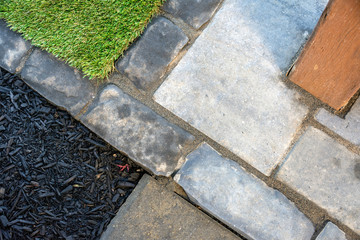 Lanscape construction detail of a patio with brick edging, artificial grass and mulched flower beds.