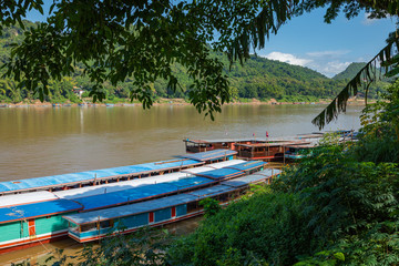 Obraz premium Traditional Long Boat on the Mekong River and mountains view in Luang Prabang, Laos.