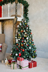 Beautiful Christmas tree with red, white and gold balls and gifts under it in the living room of the house or apartment