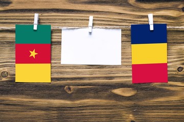 Hanging flags of Cameroon and Chad attached to rope with clothes pins with copy space on white note paper on wooden background.Diplomatic relations between countries.