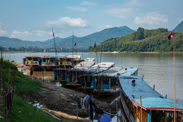 Traditional Long Boat on the Mekong River and mountains view in Luang Prabang, Laos.