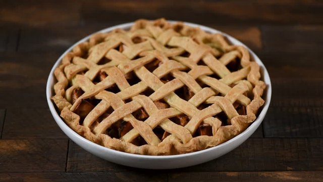 Traditional american apple pie on a wooden table. Female hands put dish with freshly baked apple pie