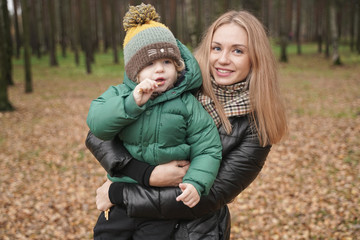 Fototapeta na wymiar caucasian young mother and little child having fun in autumn Park, walking