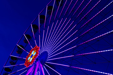 Colorful ferriswheel in vivid neon colors and a dark blue sky