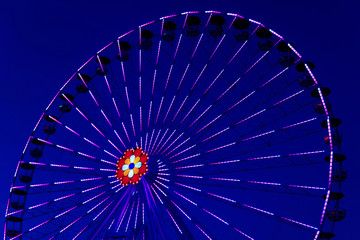 Colorful ferriswheel in vivid neon colors during evening with a dark blue sky