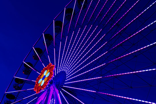Colorful ferriswheel in vivid neon colors and a dark blue sky