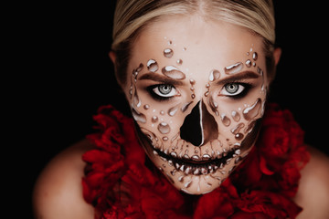 Portrait of a woman with sugar skull makeup over red background. Halloween costume and make-up. Portrait of Calavera Catrina