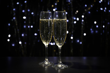 Champagne glasses against dark background with blurred lights, copy space