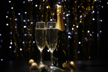 Christmas baubles, champagne glasses and bottle on blurred background, copy space