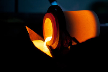 pouring liquid red metal from cast mold