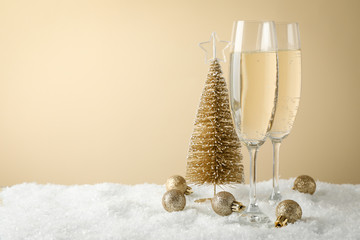 Champagne glasses and baubles against beige background, space for text