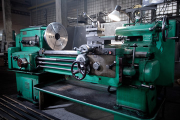 closeup of metallic lathe working against factory industrial interior background