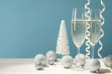 Champagne glasses and baubles against blue background, space for text