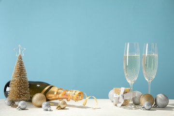 Baubles, champagne glasses and bottle against blue background, space for text