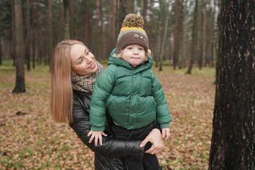 caucasian young mother and little child having fun in autumn Park, walking