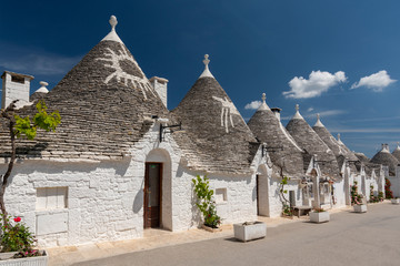 Row of traditional whitewashed trulli houses with conical roofs in Alberobello, Puglia, southern Italy.