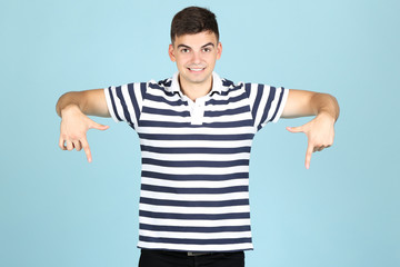 Young man showing fingers down on blue background