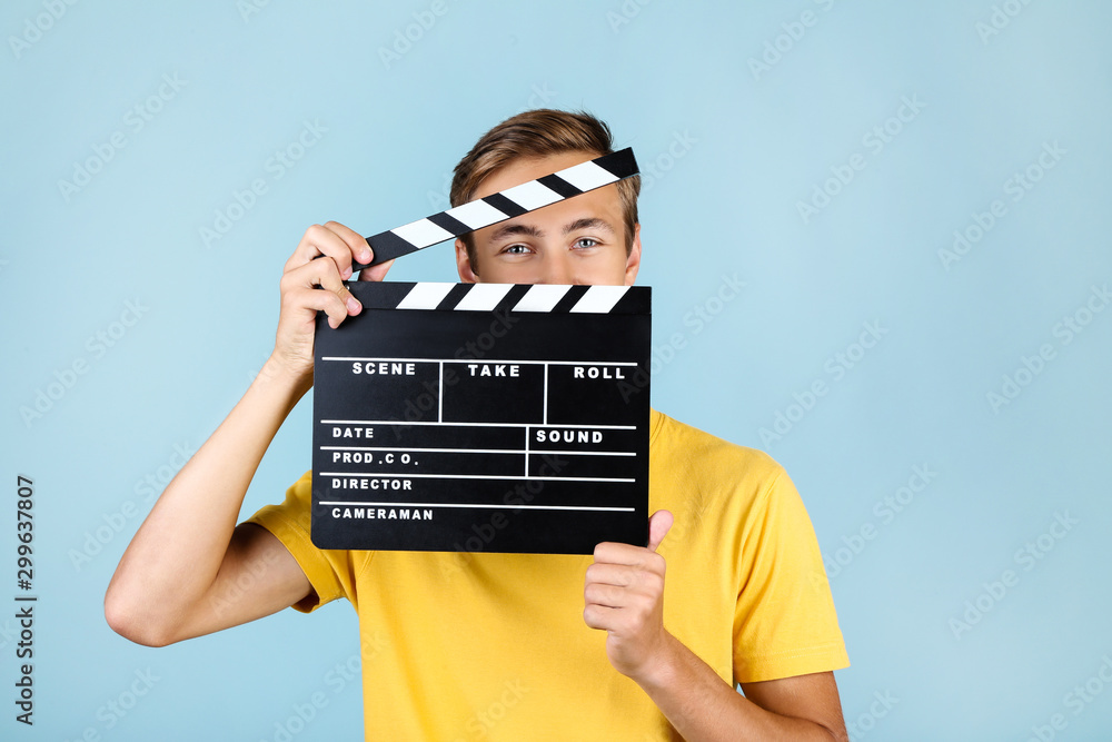 Sticker Young man with clapper board on blue background