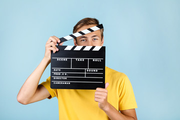 Young man with clapper board on blue background