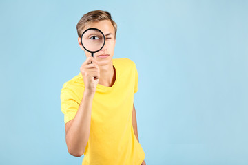 Young man with magnifying glass on blue background