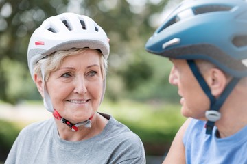 Fototapeta na wymiar Senior woman wearing cycling helmet while looking at man