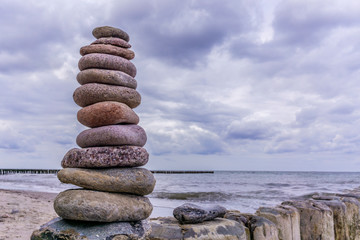Stones balanced on the beach of blue sea in cloudy weather