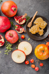 Rosh hashanah - jewish New Year holiday concept. Traditional symbols: Honey jar and fresh apples with pomegranate and shofar -horn on a black  background. Copy space for text. View from above