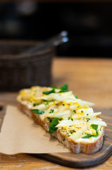 Close-up of the delicious sandwich with white asparagus and cooked egg laying on the wooden board.