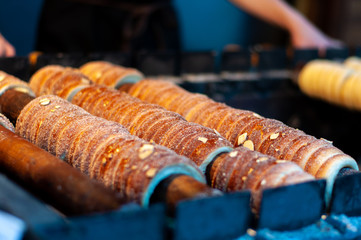 Close up of cooking the traditional sweet Czech pastry, trdelnik. Cylindrical pastry product made by winding the soft dough on a roller called 'trdlo'.