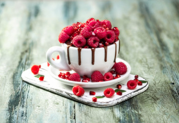 Raspberry mug cake in a red ceramic mug on wooden background
