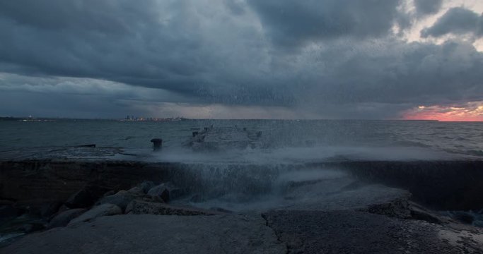 Cross shaped pier at stormy night water cascade from wave crash in slow motion