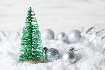 Christmas fir tree decoration with sparkling silver balls in the snow.