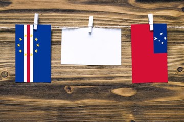 Hanging flags of Cape Verde and Samoa attached to rope with clothes pins with copy space on white...