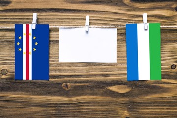 Hanging flags of Cape Verde and Sierra Leone attached to rope with clothes pins with copy space on...