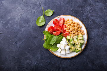 Buddha Bowl with Avocado, chickpea, feta cheese,  fresh spinach, Tomatoes and glass of water. Concept for  healthy vegetarian detox balanced  meal. Top view. Copy space.