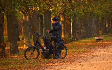 Fototapeta premium man in a helmet stands near a bicycle with a phone and a note in his hand