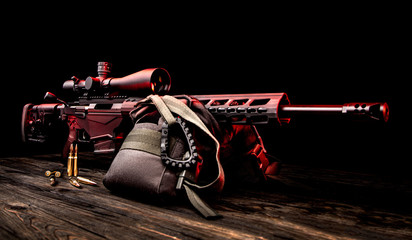 Modern sniper rifle in red backlight on a dark background. Long range shooting weapons. Weapon for...