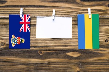 Hanging flags of Cayman Islands and Gabon attached to rope with clothes pins with copy space on...