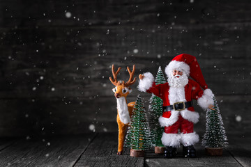 Toy of Santa Claus and deer on wooden rustic background with New year trees